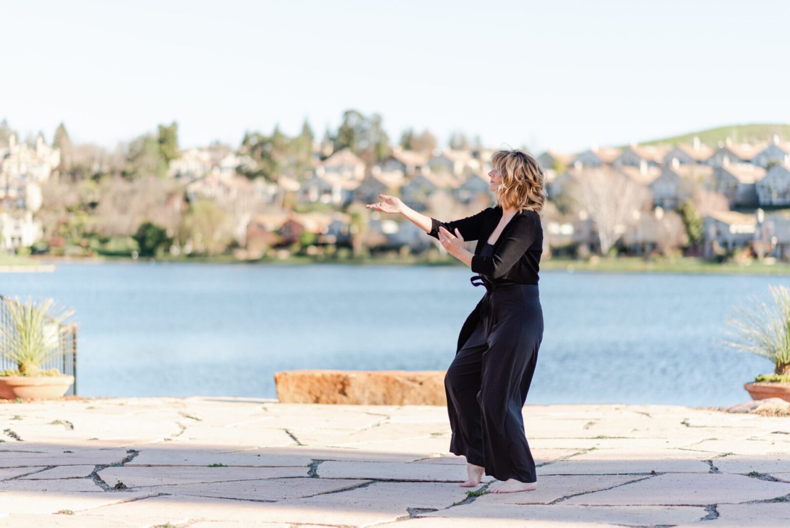 Woman practicing tai chi by a lake.