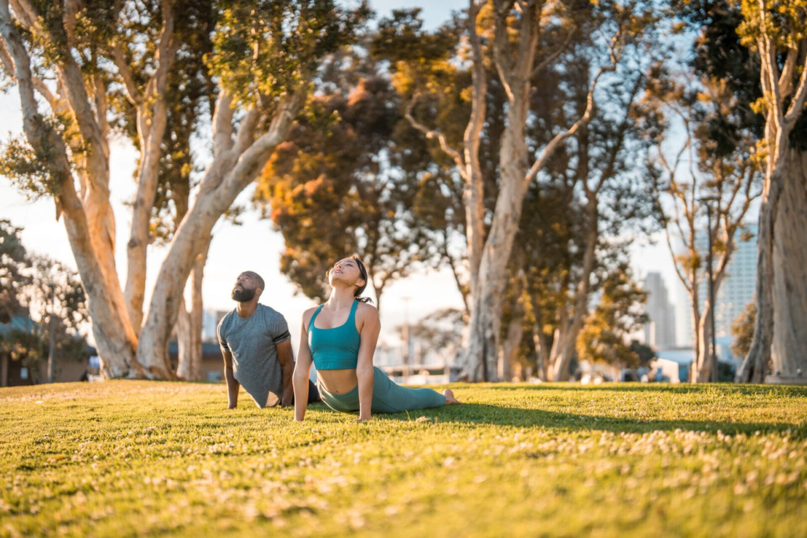 People practicing yoga outdoors in a park.