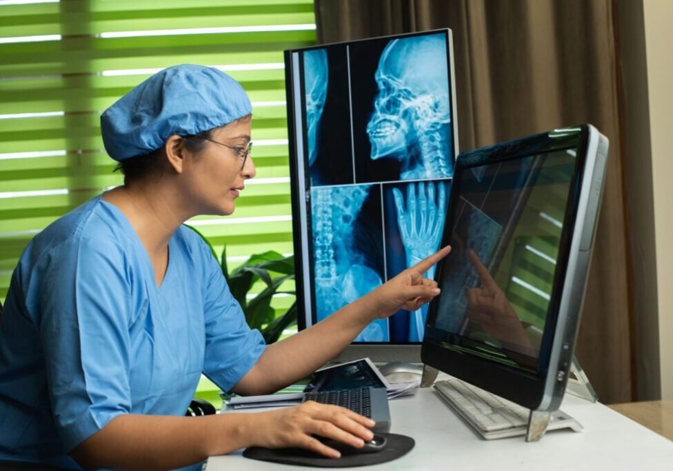 Doctor analyzing X-ray on computer screen.