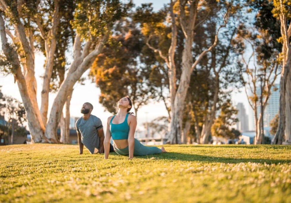 People practicing yoga outdoors in a park.